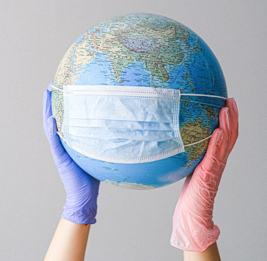 hands with latex gloves holding a globe with a face mask